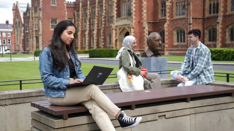 female student sitting outside Queen's main entrance